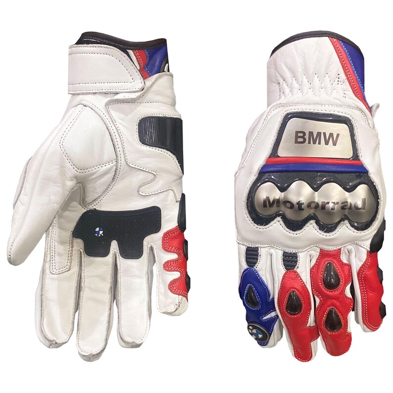 May include: White leather motorcycle gloves with black, red, and blue accents. The gloves feature the BMW logo and the word "Motorrad". The gloves have protective padding on the knuckles and wrist straps.