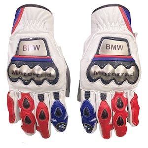 May include: A pair of white leather motorcycle gloves with red, blue, and silver accents. The gloves feature the BMW logo and the word "Motorrad". The fingers and knuckles have protective padding.