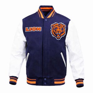 Puede incluir: Una chaqueta universitaria azul marino con mangas blancas, que presenta un gráfico de cabeza de león naranja y blanco en el pecho y la palabra LION en letras naranjas. La chaqueta tiene puños, cuello y dobladillo acanalados con rayas naranjas.