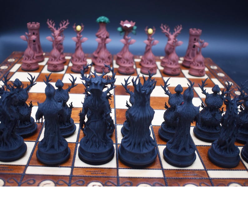 May include: A unique chess set with intricately designed pieces. The dark pieces are black tree-like figures, while the light pieces are brown with deer-like antlers and floral accents. The set is displayed on a wooden chessboard.