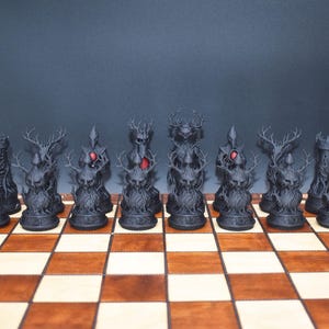 May include: A complete chess set with black, fantasy-themed pieces, including rooks, knights with antlers, and a king and queen with red accents. The pieces are arranged on a wooden chessboard with light and dark squares.