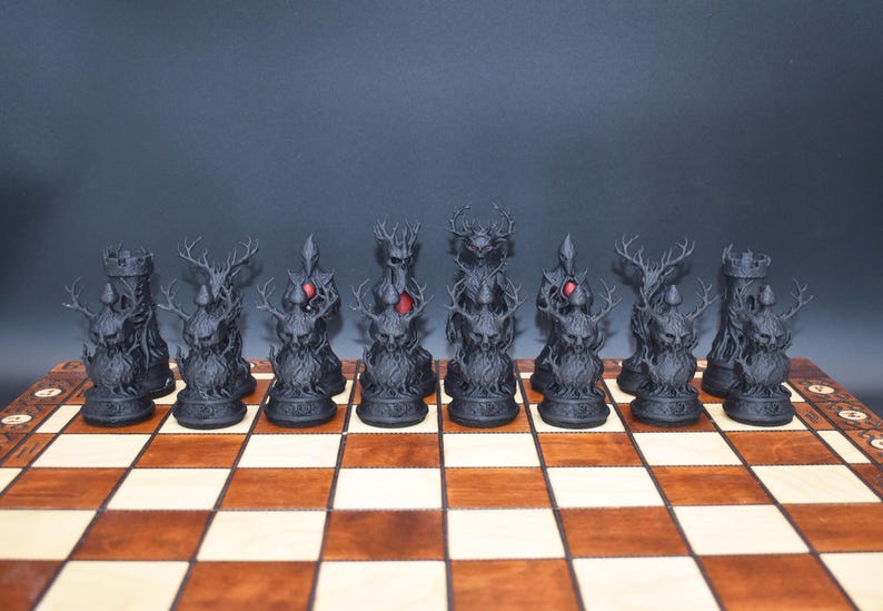 May include: A complete chess set with black, fantasy-themed pieces, including rooks, knights with antlers, and a king and queen with red accents. The pieces are arranged on a wooden chessboard with light and dark squares.