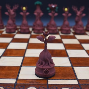 May include: A unique chess set featuring burgundy-colored pieces with detailed designs, including towers, deer, and other fantasy figures. The chess pieces are arranged on a wooden chessboard with light and dark squares. The focus is on a single piece in the foreground.