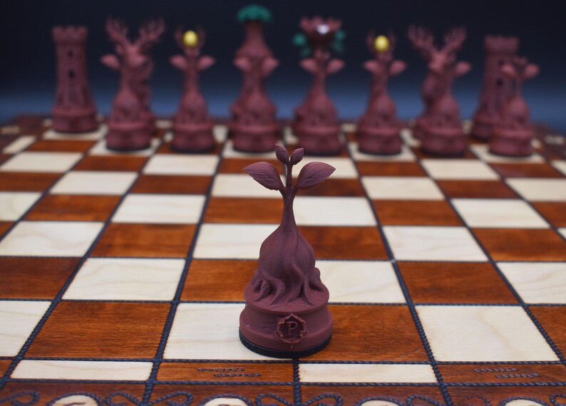 May include: A unique chess set featuring burgundy-colored pieces with detailed designs, including towers, deer, and other fantasy figures. The chess pieces are arranged on a wooden chessboard with light and dark squares. The focus is on a single piece in the foreground.