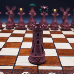 May include: A close-up of a burgundy chess set on a wooden chessboard. The focus is on a castle piece with a detailed, textured design. Other pieces, including deer and tree-shaped figures, are visible in the background. The board has light and dark squares.