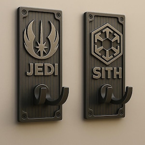 以下が含まれることがあります： ダークブロンズの壁掛けフック2つ。片方は「JEDI」の文字と様式化されたエンブレム、もう片方は「SITH」の文字と幾何学的なエンブレム。各フックは二股のデザインで、長方形のプレートに取り付けられています。
