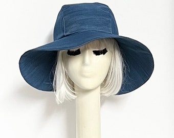 May include: A wide-brimmed hat in a deep blue color. The hat is made of a soft, textured fabric and has a slightly curved brim.