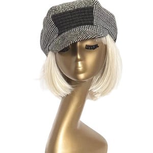 May include: A patchwork newsboy cap with a black, gray, and green color scheme. The cap features a classic newsboy style with a short brim and a rounded crown. The cap is displayed on a gold mannequin head with blonde hair.