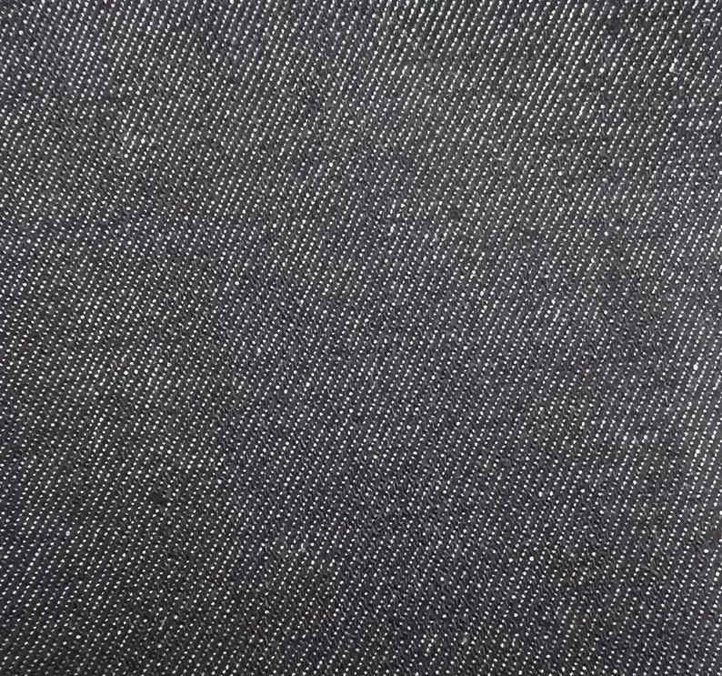 May include: Close-up of a dark gray denim fabric with a diagonal weave pattern.