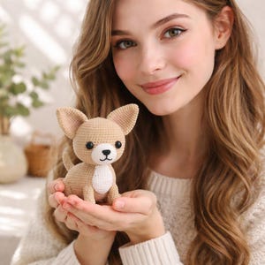 Könnte beinhalten: Ein gehäkelter Chihuahua-Hund in Beige und Weiß. Der handgefertigte Amigurumi-Hund hat große Ohren, schwarze Augen und eine kleine schwarze Nase. Der Hund sitzt aufrecht mit eingerollter Rute. Es ist ein niedliches, handgemachtes Produkt.