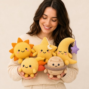 May include: A collection of five knitted plush toys featuring celestial themes: a bright yellow sun with orange rays, a yellow star with a small moon charm, a yellow crescent moon with a purple star, a yellow comet, and a beige planet with rings.