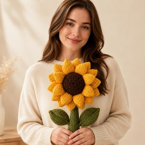 May include: A handcrafted crochet sunflower plush featuring a dark brown centre, vibrant yellow petals, and a green stem with two matching green leaves. The flower is constructed with visible yarn stitches, creating a textured, three-dimensional appearance.