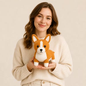 Può includere: Un piccolo peluche a forma di corgi lavorato a maglia a mano, caratterizzato da un motivo color arancione e bianco. Il giocattolo presenta orecchie a punta, petto e macchia sul muso bianchi, occhi a bottone neri e un naso ricamato.