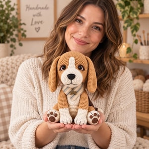 May include: A crocheted beagle puppy toy with brown, white, and black yarn. The plush dog features long floppy ears, dark plastic eyes, a black stitched nose, and white paws with brown pads. It wears a beige and blue striped bandana with a small bone charm.
