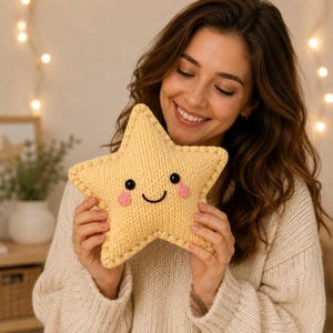 Peut inclure: Un coussin en peluche en forme d'étoile jaune avec une texture tricotée. Le coussin présente un visage brodé amical avec deux yeux circulaires noirs, une bouche noire incurvée et deux petites joues circulaires roses cousues au centre.