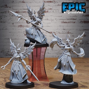 May include: Three grey miniature figurines of winged warrior women. One figure is seated and holding a spear, while the other two are standing and holding weapons. The figurines have detailed armour and flowing robes. The text "EPIC Miniatures" is in the upper right corner.