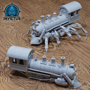 May include: Two gray miniature train models with spider-like legs. One model is fully assembled, while the other is partially assembled. The trains have detailed features, including smokestacks, a cab, and a front cowcatcher. The Invictus Miniatures logo is in the upper left corner.