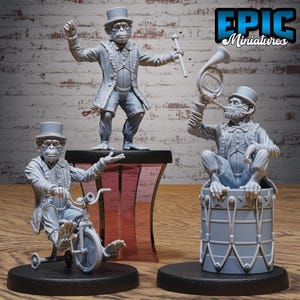 Puede incluir: Tres figuras de monos grises con atuendo de circo. Un mono está de pie sobre un pedestal, otro monta en triciclo y el tercero toca una trompa sentado en un tambor. El texto "EPIC Miniatures" está en la esquina superior derecha.