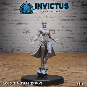 Könnte beinhalten: Graue Miniaturfigur einer Kriegerin mit ausgestreckten Armen, in futuristischer Rüstung und einem langen Mantel. Die Figur steht auf einer kleinen Plattform. Der Text "INVICTUS MINIATURES" steht darüber. Sockelgröße: Medium (2,55 cm).