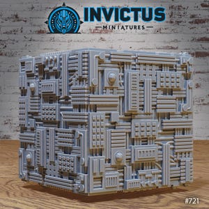 Puede incluir: Una miniatura gris en forma de cubo con intrincados detalles geométricos. La superficie está cubierta por una red de tuberías, paneles y elementos circulares. La palabra "INVICTUS" está impresa en la parte superior y el número "#721" en la parte inferior.