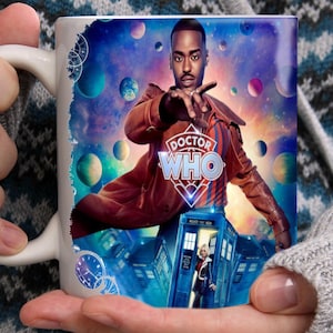 Peut inclure: Mug en céramique blanche avec une image colorée d'un homme en manteau marron et le texte "Doctor Who". Le design comprend une cabine téléphonique bleue et un fond spatial.