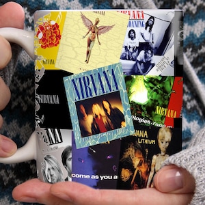 May include: White ceramic mug decorated with a collage of Nirvana album artwork. The mug showcases album covers such as "Nevermind" and "In Utero," with diverse colours and graphics. A distinctive gift for music enthusiasts.