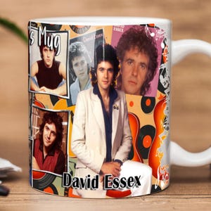 Pode incluir: Caneca de cerâmica branca com uma colagem de imagens de David Essex, o texto "David Essex" e "Mug". O design inclui detalhes em laranja, vermelho e preto, com notas musicais e gráficos de discos de vinil.