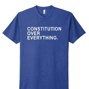 Puede incluir: Una taza de cerámica blanca con un asa negra y el texto "But First, Coffee" en negro, con una fuente de estilo manuscrito. La taza está sobre una superficie blanca.