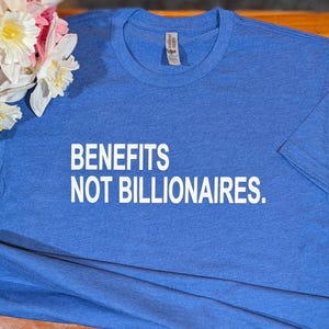 May include: A blue t-shirt with the text "BENEFITS NOT BILLIONAIRES." printed in white.