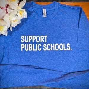 May include: A royal blue t-shirt with the text "SUPPORT PUBLIC SCHOOLS." printed in white.