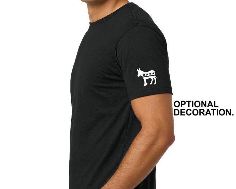 Puede incluir: Camiseta negra de manga corta con un dise&ntilde;o de burro y estrellas blancas en la manga izquierda. El texto "OPTIONAL DECORATION" est&aacute; impreso en negro en el lado derecho de la imagen.