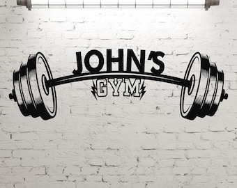 May include: Black and white illustration of a barbell with weights on each end. The barbell is arched and the text "JOHN'S GYM" is written above it.