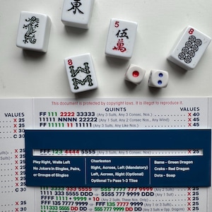 May include: A collection of white Mahjong tiles with black and red symbols and numbers, including the character for "East" and the number "5". Two dice with red and blue dots are also present, along with a game guide.