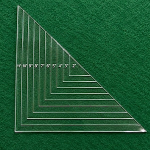 May include: A clear acrylic right-angled triangle quilting ruler featuring etched markings from 2 inches to 11 inches. The tool displays nested triangular outlines with corresponding numerical labels for precise fabric cutting and measuring.