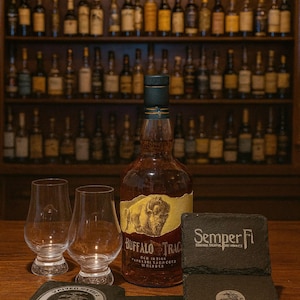 Könnte beinhalten: Eine Flasche Buffalo Trace Bourbon, zwei Gläser und Schieferuntersetzer mit den Worten "Semper Fi" und "Marines". Im Hintergrund ein Regal mit verschiedenen Spirituosenflaschen.