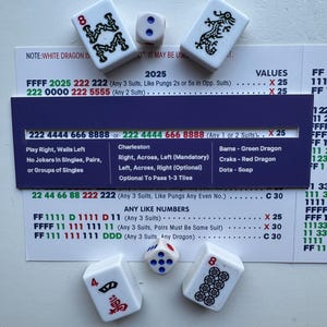May include: A collection of white Mahjong tiles with black symbols and numbers, along with a die. The tiles feature dragons, flowers, and the number eight. A game instruction sheet is also visible.