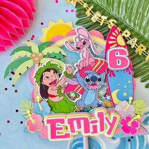 K&ouml;nnte beinhalten: Ein farbenfroher Tortenaufsatz mit den Zeichentrickfiguren Stitch, Lilo und Angel. Das Design umfasst ein Surfbrett, einen Regenbogen und die Zahl 6. Der Name "Emily" ist prominent dargestellt, umgeben von tropischen Blumen und Palmen.