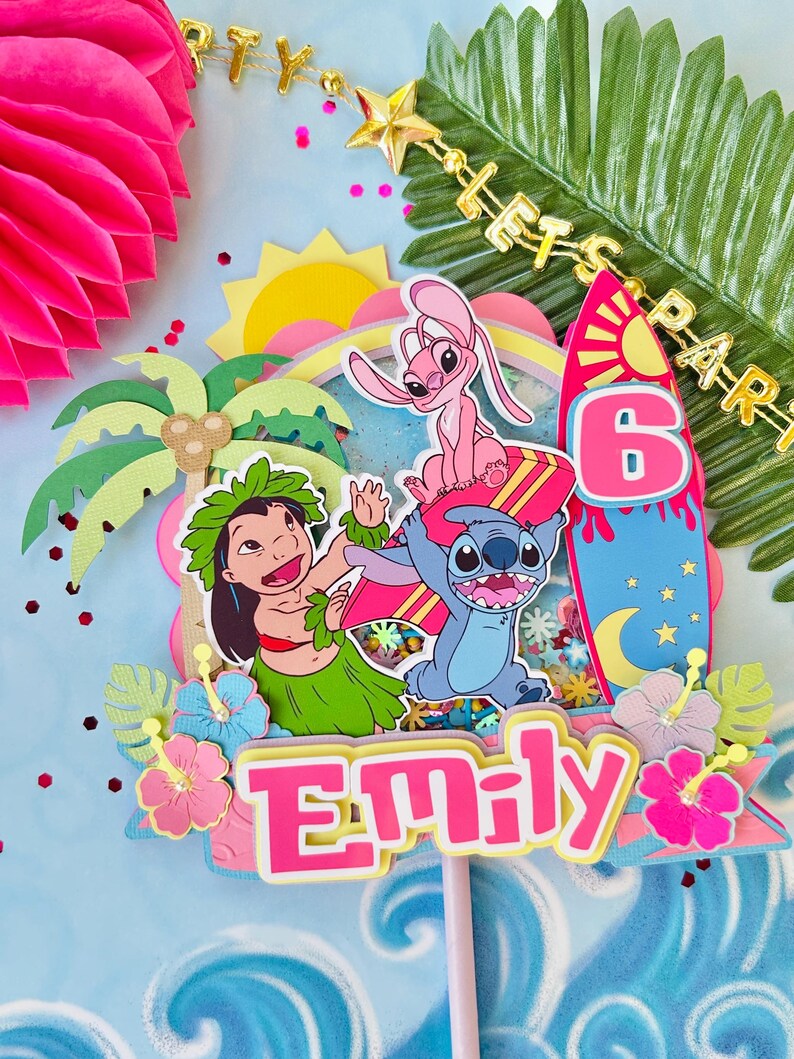 K&ouml;nnte beinhalten: Ein farbenfroher Tortenaufsatz mit den Zeichentrickfiguren Stitch, Lilo und Angel. Das Design umfasst ein Surfbrett, einen Regenbogen und die Zahl 6. Der Name "Emily" ist prominent dargestellt, umgeben von tropischen Blumen und Palmen.