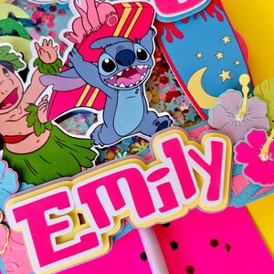 K&ouml;nnte beinhalten: Ein lebendiger Tortenaufsatz mit dem Namen "Emily" in leuchtendem Pink mit gelbem Rand. Er zeigt Cartoonfiguren, ein Surfbrett und die Zahl "6". Das Design hat ein tropisches Thema mit gelbem Hintergrund.