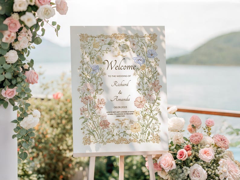 May include: A wedding welcome sign on an easel, featuring floral artwork and the names Richard & Amanda. The sign is surrounded by flowers in shades of pink, white, and yellow. The text reads "Welcome" and the wedding date.