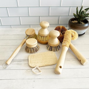 May include: A set of seven natural cleaning tools, including a loofah sponge, a brush with a wooden handle, and five different types of scrub brushes with wooden handles.