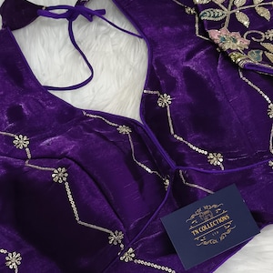 May include: A close-up of a deep purple blouse with intricate gold sequin detailing. The blouse features a V-neck design and delicate floral embroidery. A small tag with the text "TN COLLECTIONS" is visible.