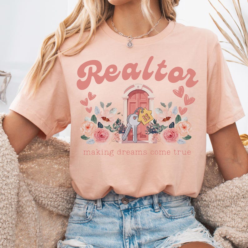 May include: A pink t-shirt with the text "Realtor" in a retro font, a pink door with keys and a house key chain, and floral accents. The text "making dreams come true" is below the image.