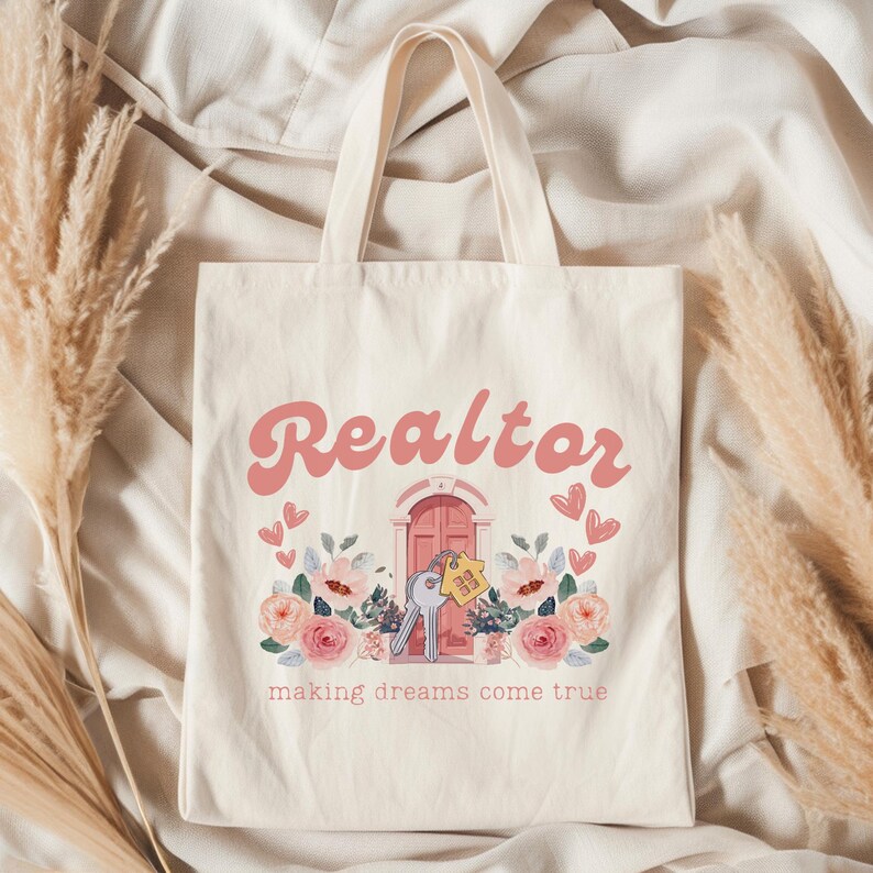 May include: A white canvas tote bag with the text "Realtor making dreams come true" in pink and a pink door with keys and flowers.