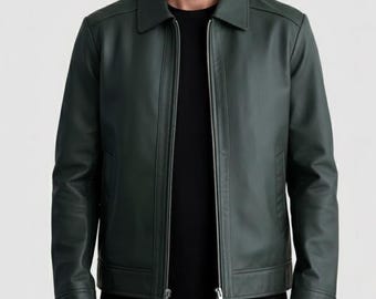 May include: A dark forest green leather jacket featuring a classic point collar, long sleeves with buttoned cuffs, and a full-length silver metal zip closure down the centre. The jacket is worn over a plain black shirt against a light grey background.