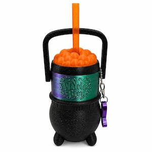 May include: A black cauldron-shaped cup with a handle, featuring a metallic green and purple band embossed with the text Witches Brew. The top has orange bubbles and an orange straw, with a small purple charm attached to the side by a silver chain.