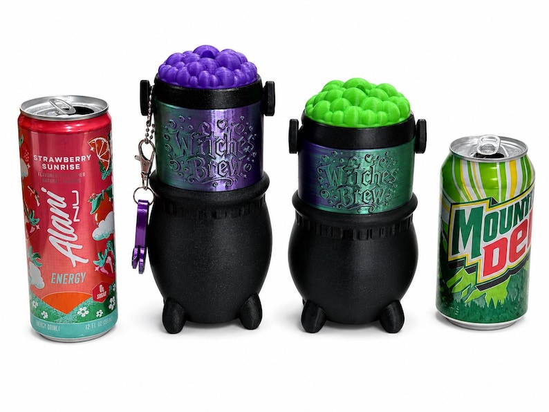 May include: Two black plastic cauldron-shaped containers with iridescent bands labeled "Witches Brew" and removable lids topped with textured purple and green bubbles, positioned between a red Alani Nu energy drink and a green Mountain Dew soda can.