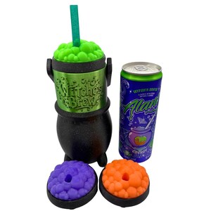 May include: A black cauldron-shaped cup with a green textured lid and a green straw, featuring the embossed text "Witch's Brew". Beside it sits a purple and green "Witch's Brew" energy drink can, along with two additional cauldron lids in purple and orange.