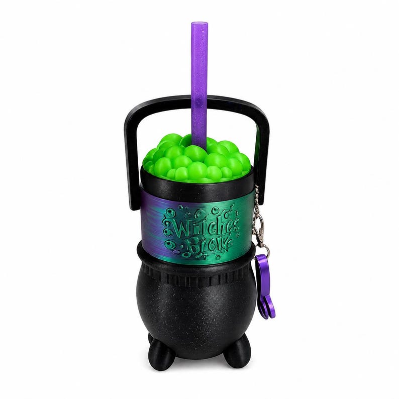 May include: A black cauldron-shaped tumbler with a handle, featuring a green bubbly top and a purple glittery straw. A metallic band around the center displays the text Witches Brew in raised lettering, accompanied by a small purple charm on a chain.