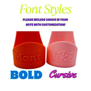 Op de afbeelding: Afbeelding van twee gepersonaliseerde telefoonstandaards. E&eacute;n is oranje met "Monte" in vette letters, de andere roze met "Niki" in cursief. De tekst bovenaan luidt "Font Styles" en "PLEASE INCLUDE CHOICE IN YOUR NOTE WITH CUSTOMIZATION!"